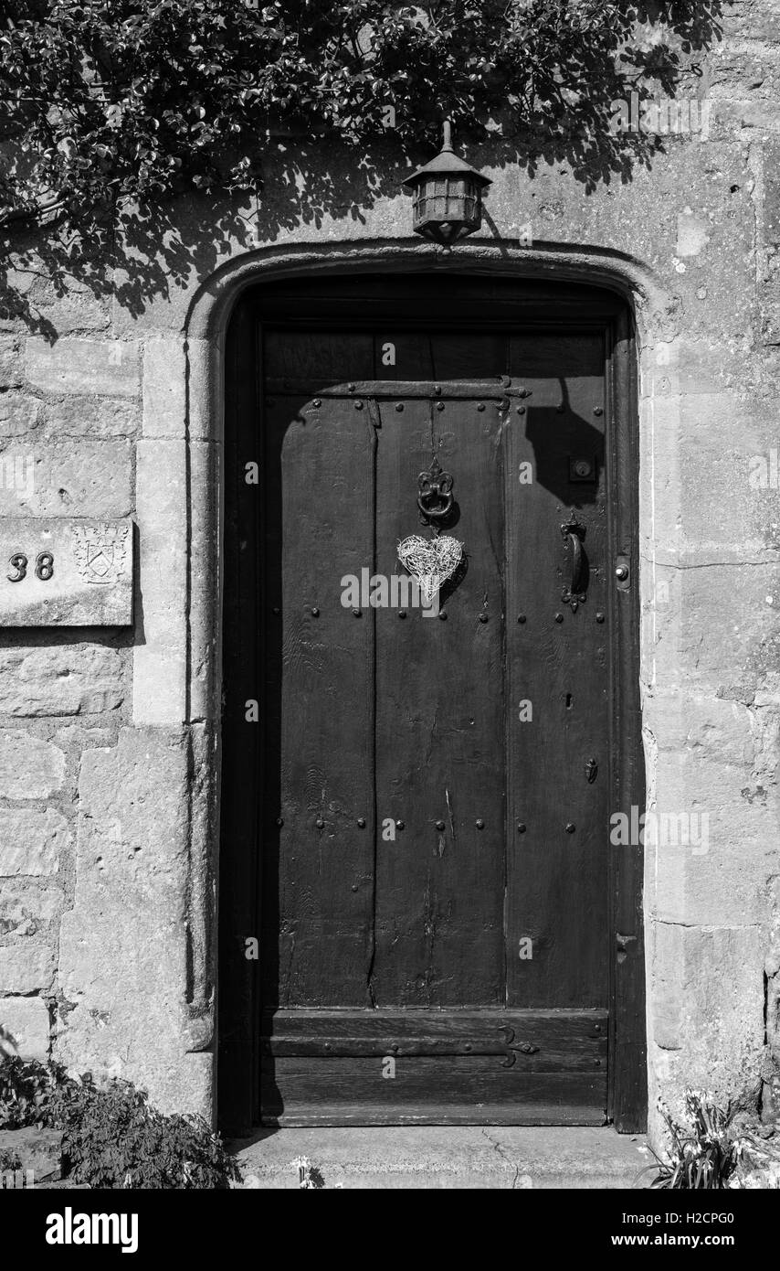 Porta di cotswold cottage in pietra con la vecchia porta di legno Foto Stock