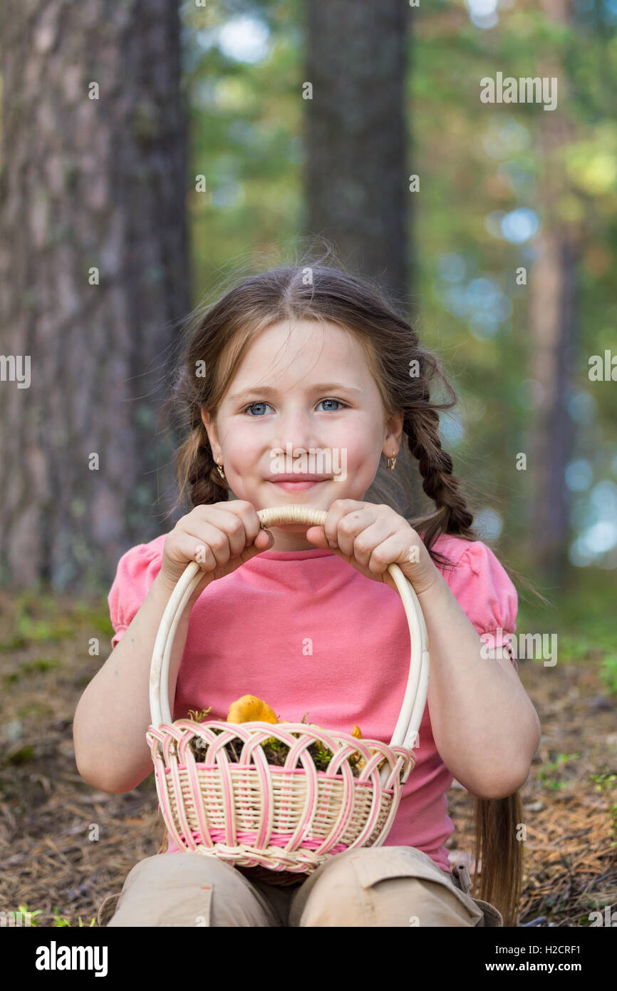 Bambina raccogliere funghi nella foresta Foto Stock