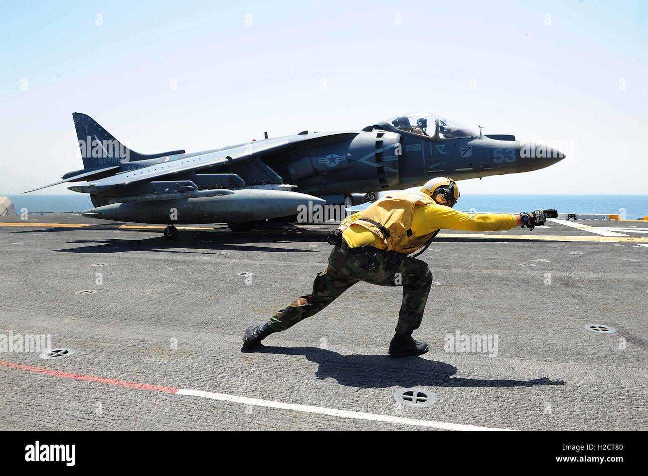 Un U.S. Navy aviation nostromi mate segnali a U.S. Marine AV-8B Harrier II attacco a terra degli aeromobili sul ponte di volo dell'USN Wasp-classe assalto anfibio nave USS Boxer Luglio 11, 2016 nel Golfo Arabico. Foto Stock