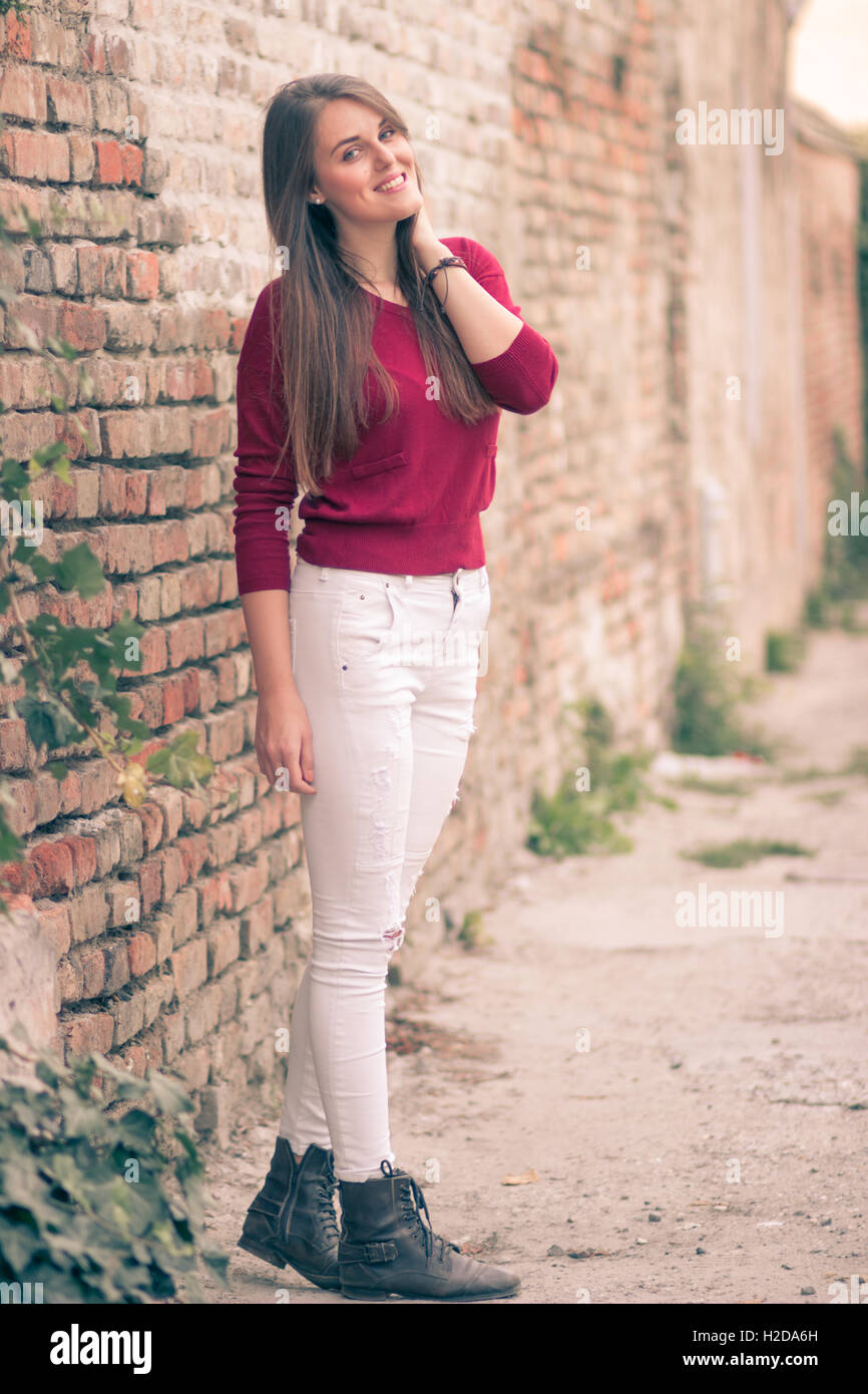 Giovane ragazza che pongono un muro di mattoni retrò colori slavati toni caldi Foto Stock