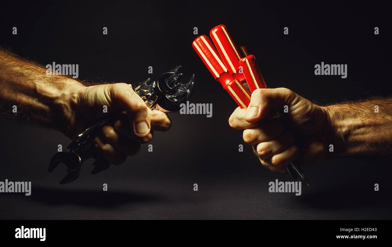 Due mani maschili sono holding set di cacciaviti e chiavi. Foto Stock