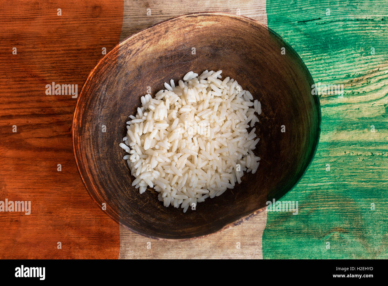 Il concetto di povertà, ciotola di riso con la bandiera della Costa d'Avorio su sfondo di legno Foto Stock