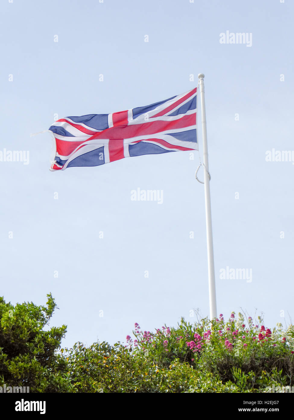 Union Jack flag volando sopra un cielo blu sullo sfondo Foto Stock