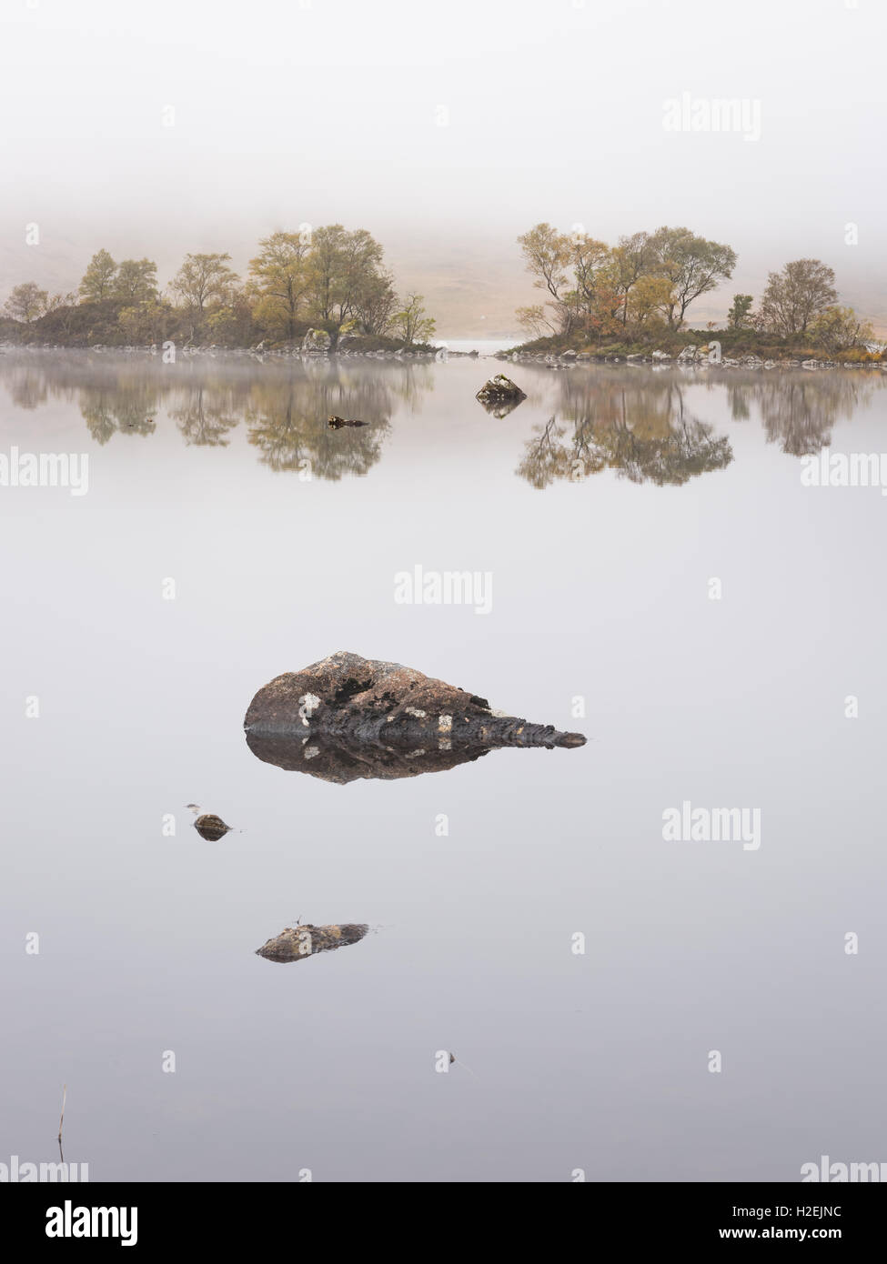 Isole riflessa in misty Lochan na h-Achlaise, Rannoch Moor, Highlands scozzesi, Scozia Foto Stock