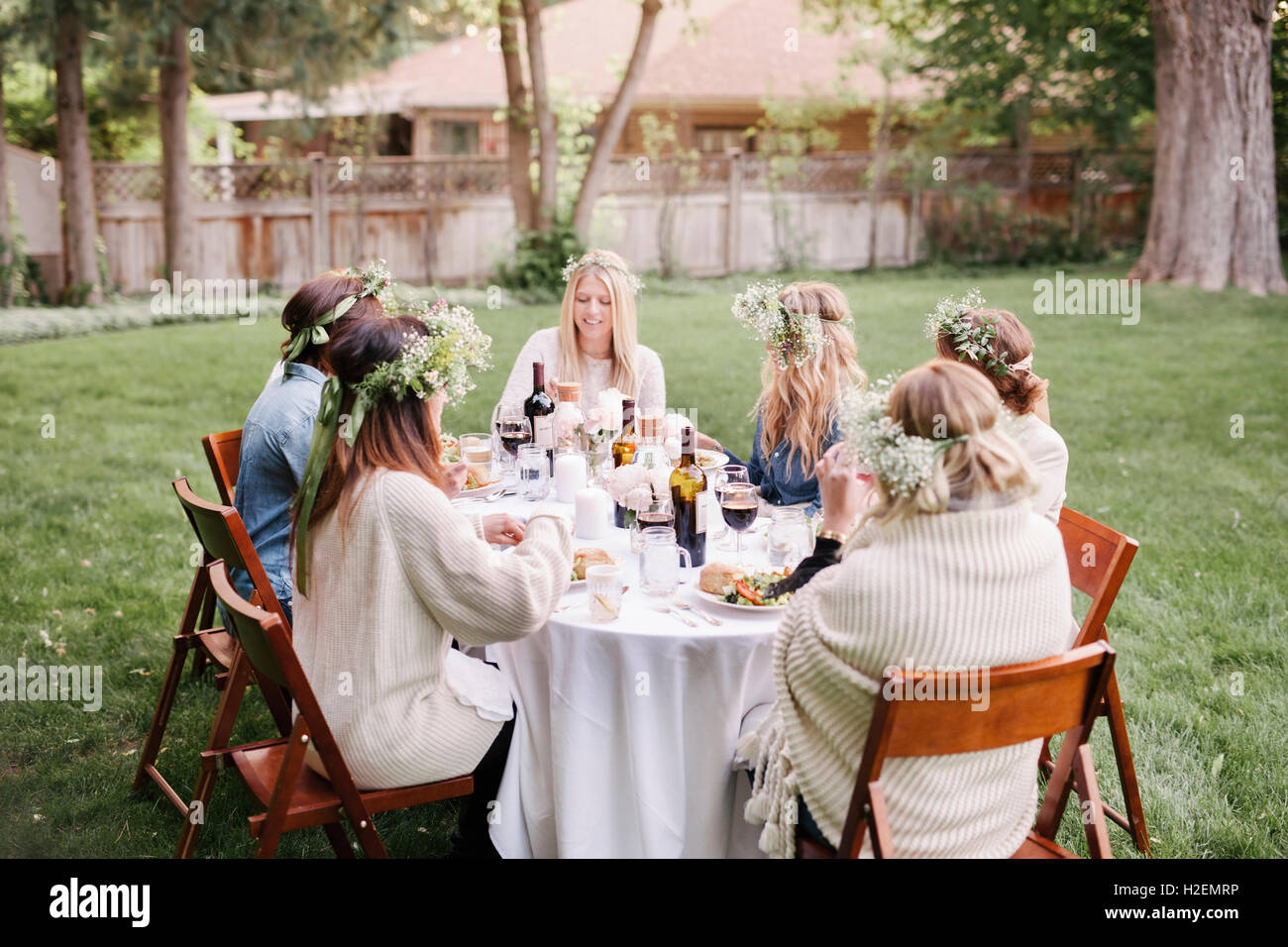 Il gruppo di amici di sesso femminile si sono riuniti intorno ad un tavolo, in un giardino di mangiare e di bere. Foto Stock