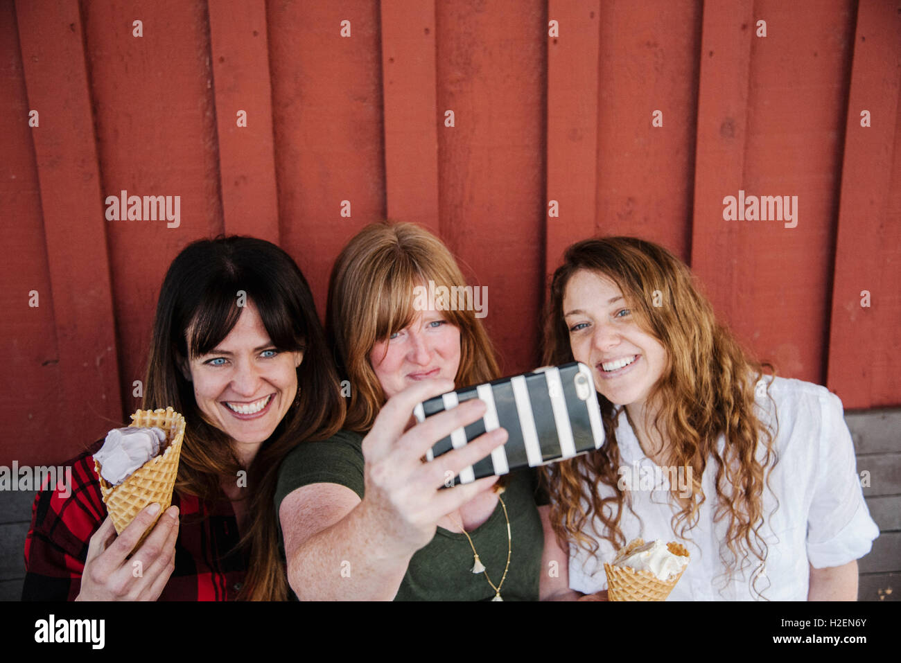Tre donne mangiare il gelato, prendendo un selfie con un telefono cellulare. Foto Stock