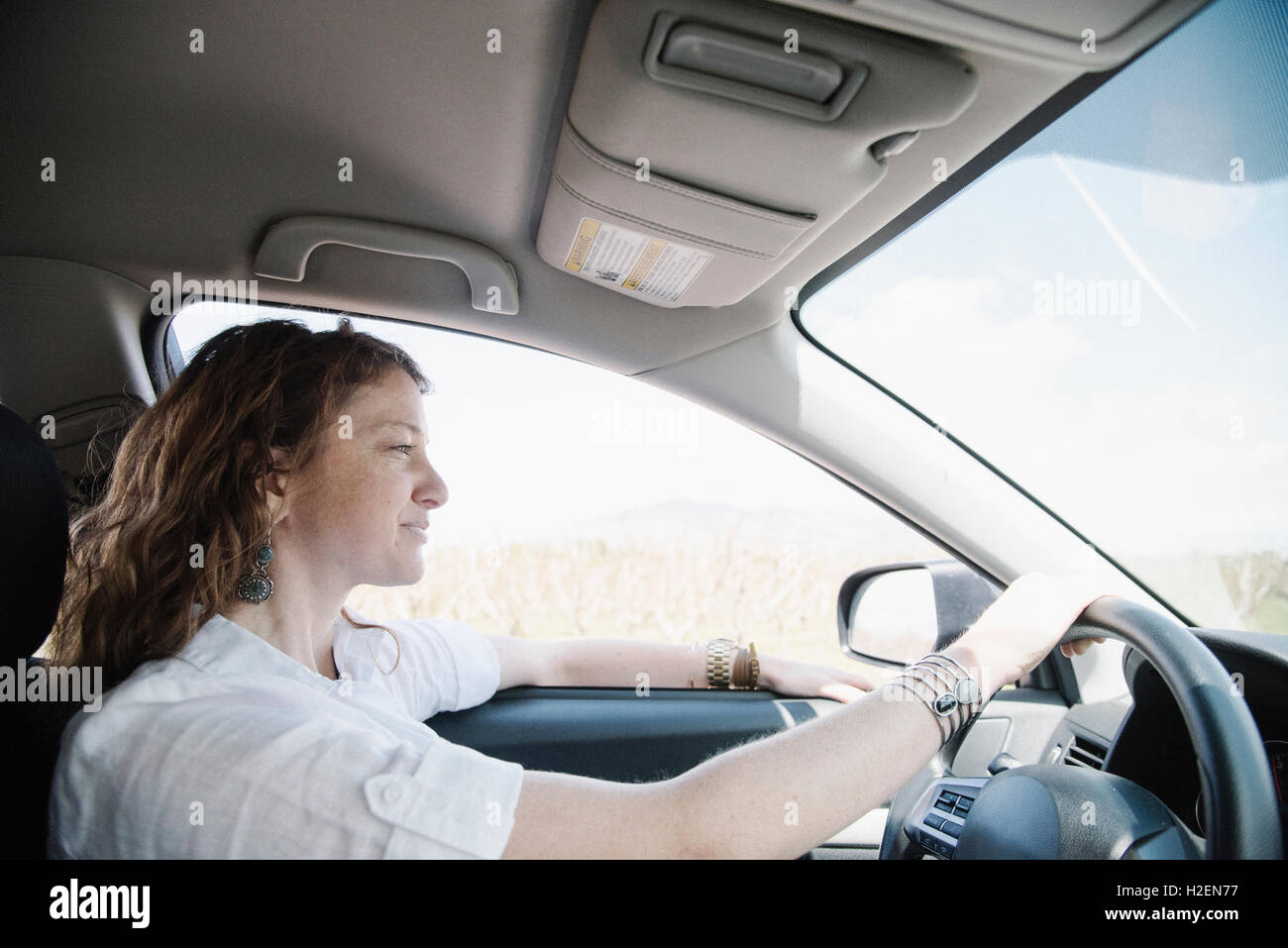 Una donna con le mani del conducente al volante. Foto Stock