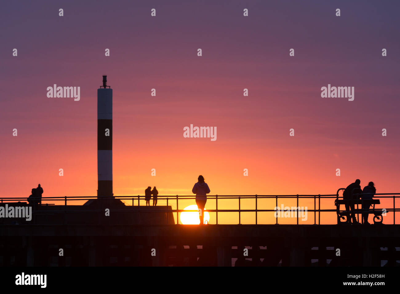 Profilarsi la gente su un molo al tramonto Foto Stock