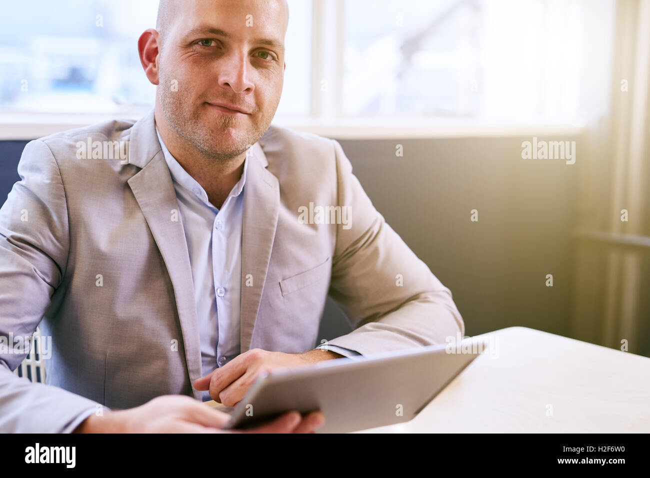 Happy business man holding tablet mentre guarda la fotocamera Foto Stock