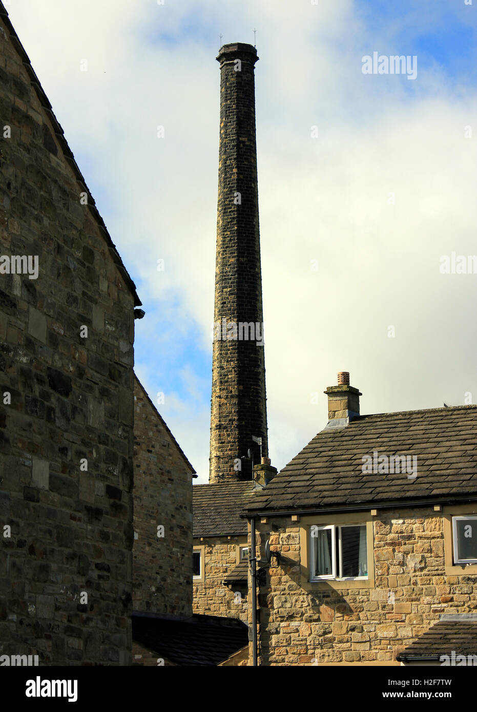 Un ex mulino tessile camino torreggia su cottages in Carleton in Craven nel North Yorkshire Foto Stock