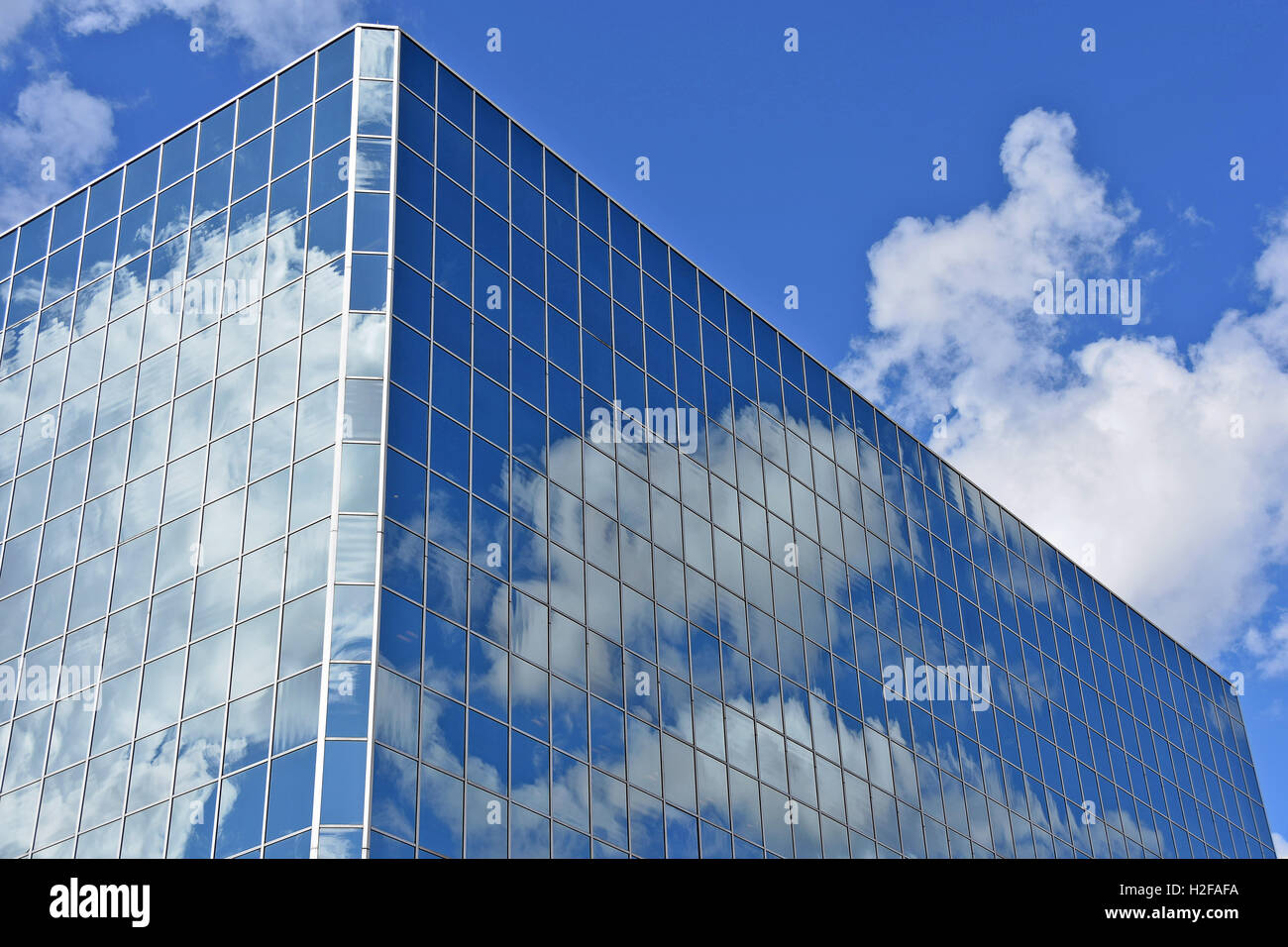Il grattacielo di vetro con cielo blu e bianca nuvola riflessione Foto Stock