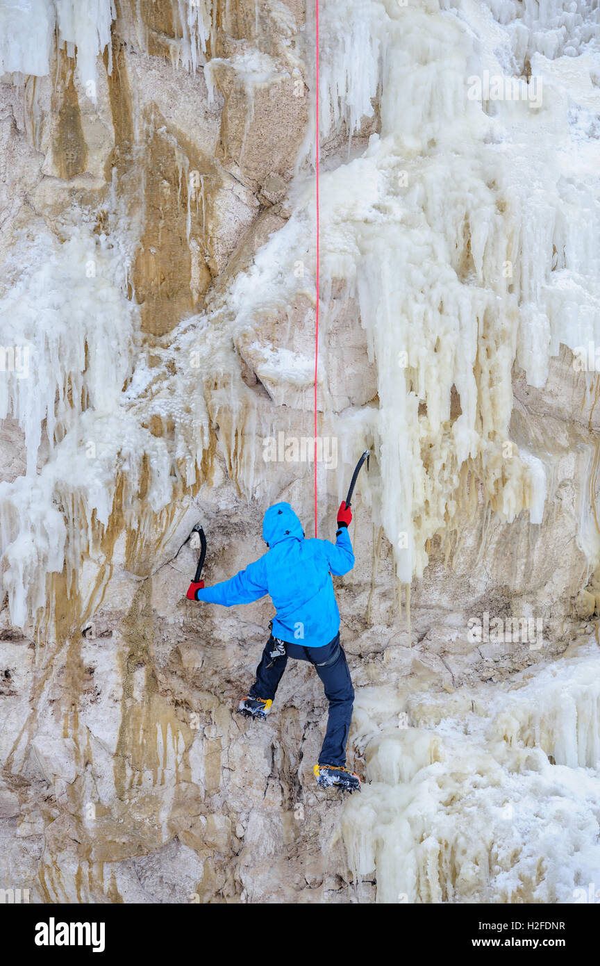 Giovane uomo arrampicata sul ghiaccio Foto Stock