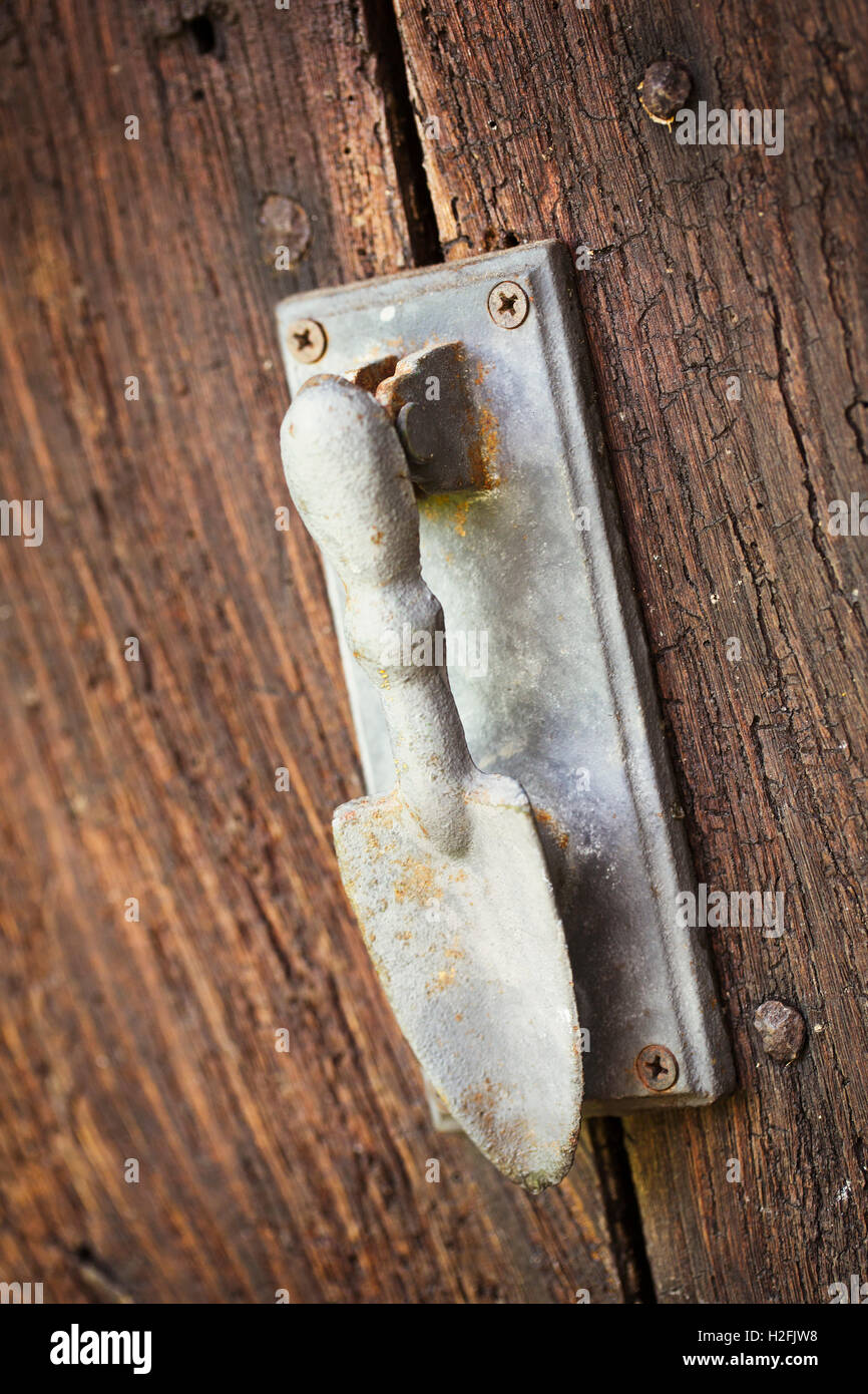 Una porta respingente su un vecchio usurato porta la forma di una mano cazzuola. Foto Stock