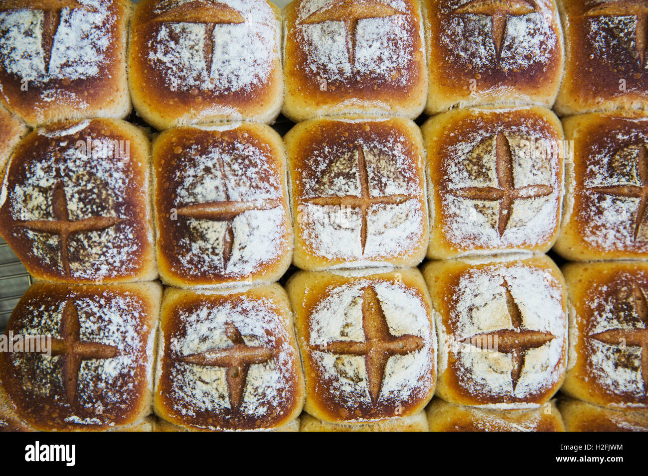 Appena sfornato pane batch rotoli infarinata con croci sulla parte superiore. Foto Stock