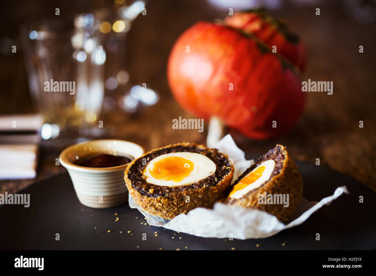 Borgo Casa pubblica il cibo. Un piatto con una fresca fatta scotch egg tagliati in due e una pentola di salsa. Foto Stock