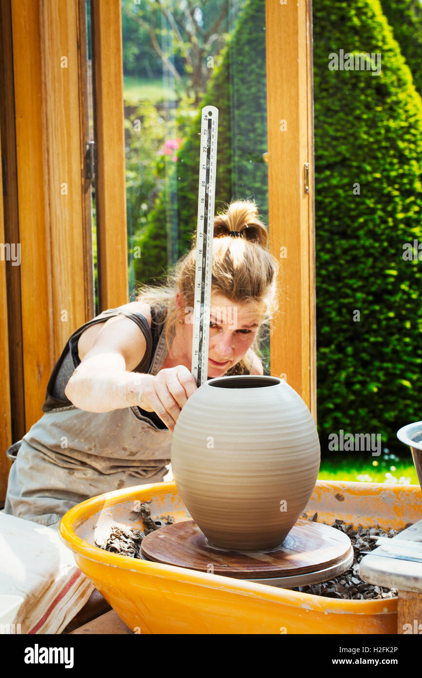 Una donna potter la misurazione di un vaso sulla ruota con un righello. Foto Stock