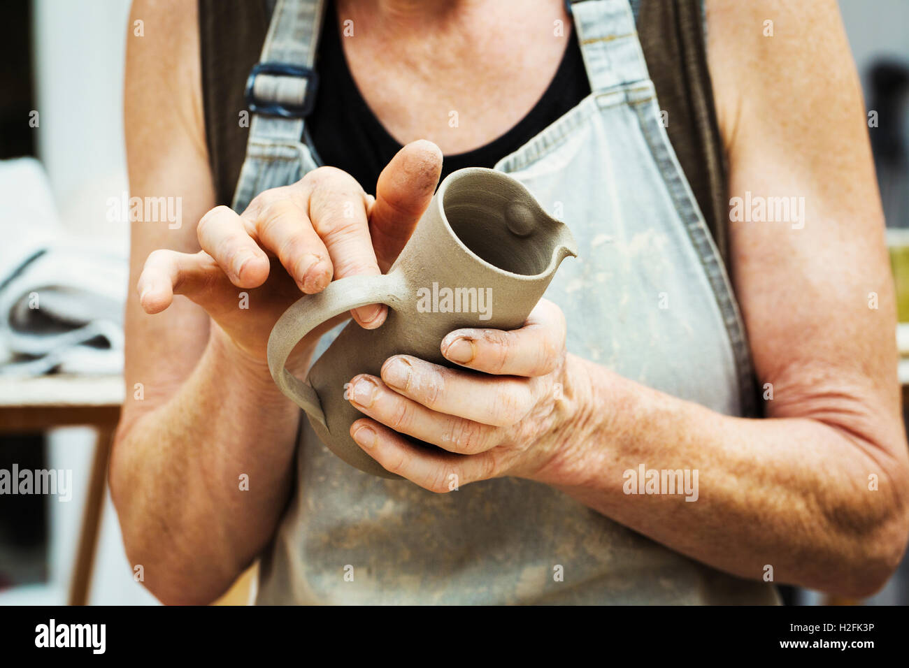 Un vasaio la manipolazione di una argilla umida pot, argilla di levigatura e prepararlo per la cottura in forno. Foto Stock