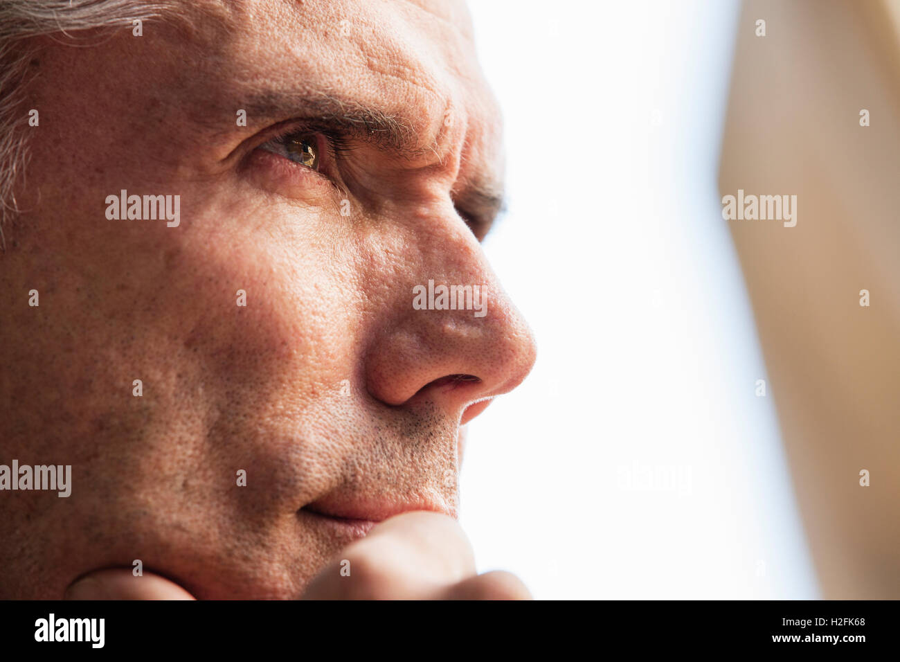 Close up di un il volto dell'uomo, la sua mano sul suo mento, guardando in lontananza. Foto Stock