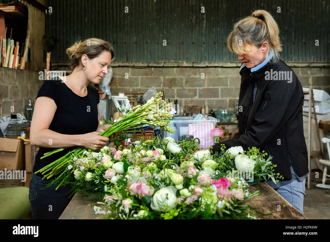 Commerciali disponendo dei fiori. Due donne in corrispondenza di un banco di lavoro creazione floreale decorazione tavola s e accordi. Foto Stock