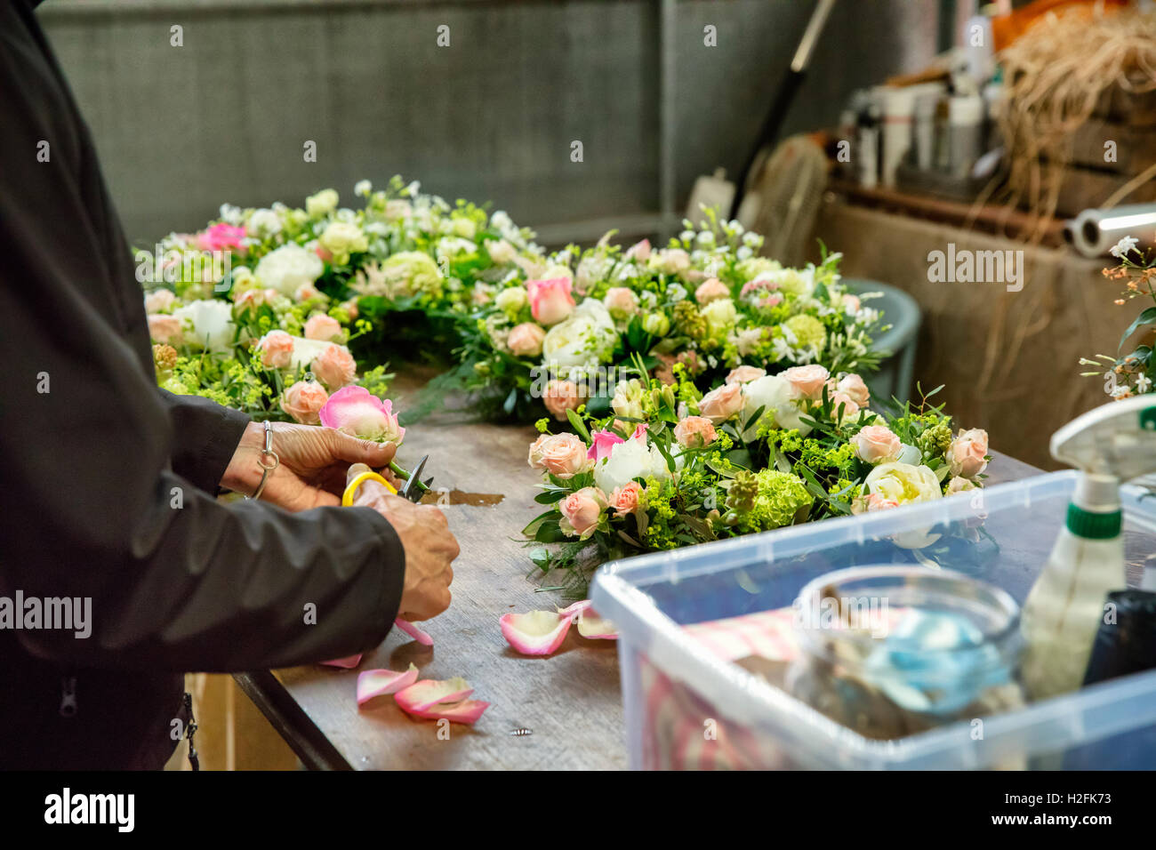 Fiorista commerciale. Una donna che lavora su una decorazione floreale in corrispondenza di un banco da lavoro. Foto Stock