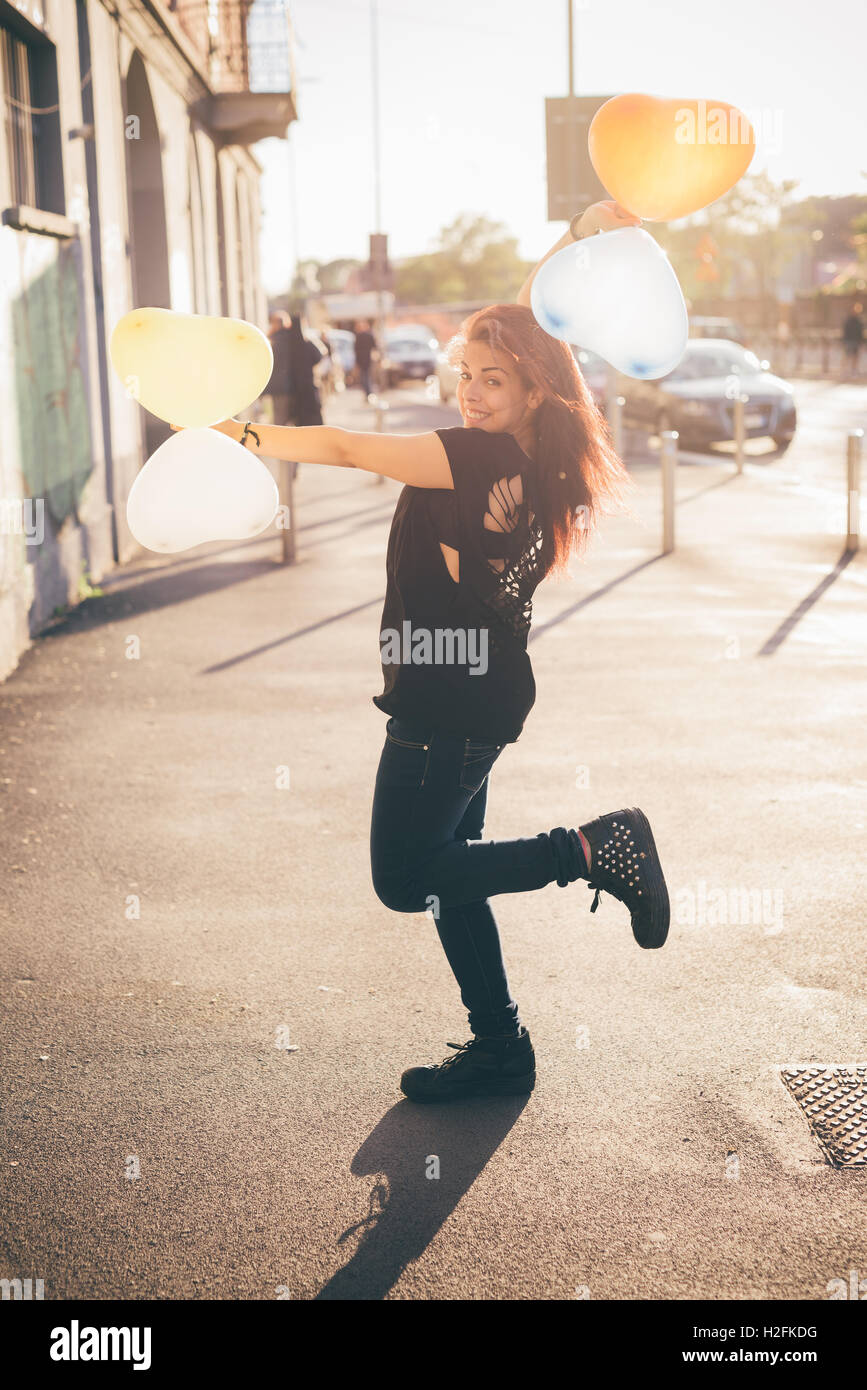Giovani marrone rossiccio capelli donna caucasica giocare in strada con il palloncino a forma di cuore - Gioventù, Infanzia, carefreeness co Foto Stock