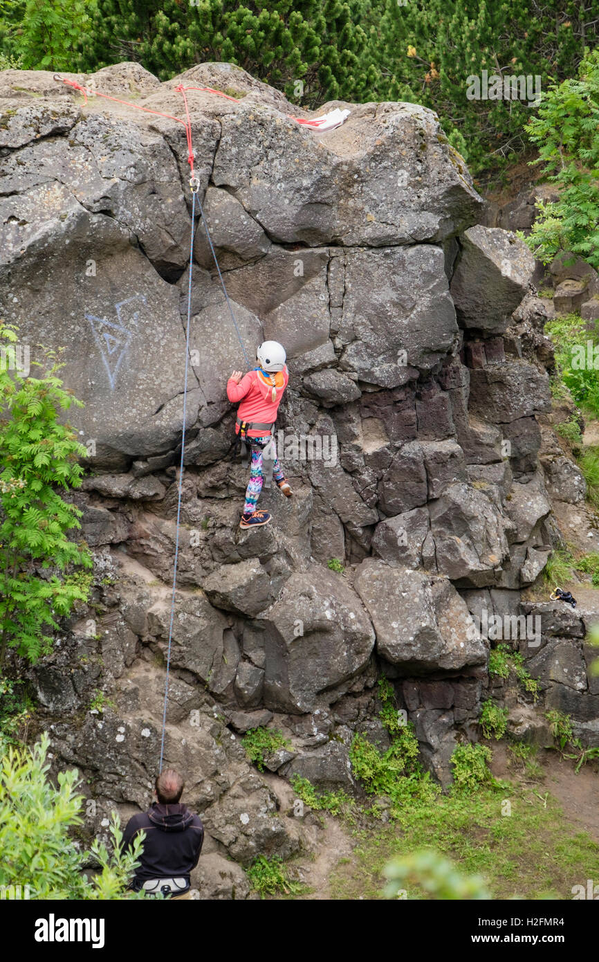 Bambino viene insegnato di arrampicata con una corda superiore su di un promontorio roccioso. Öskjuhlíð Hill, Reykjavik, Islanda Foto Stock