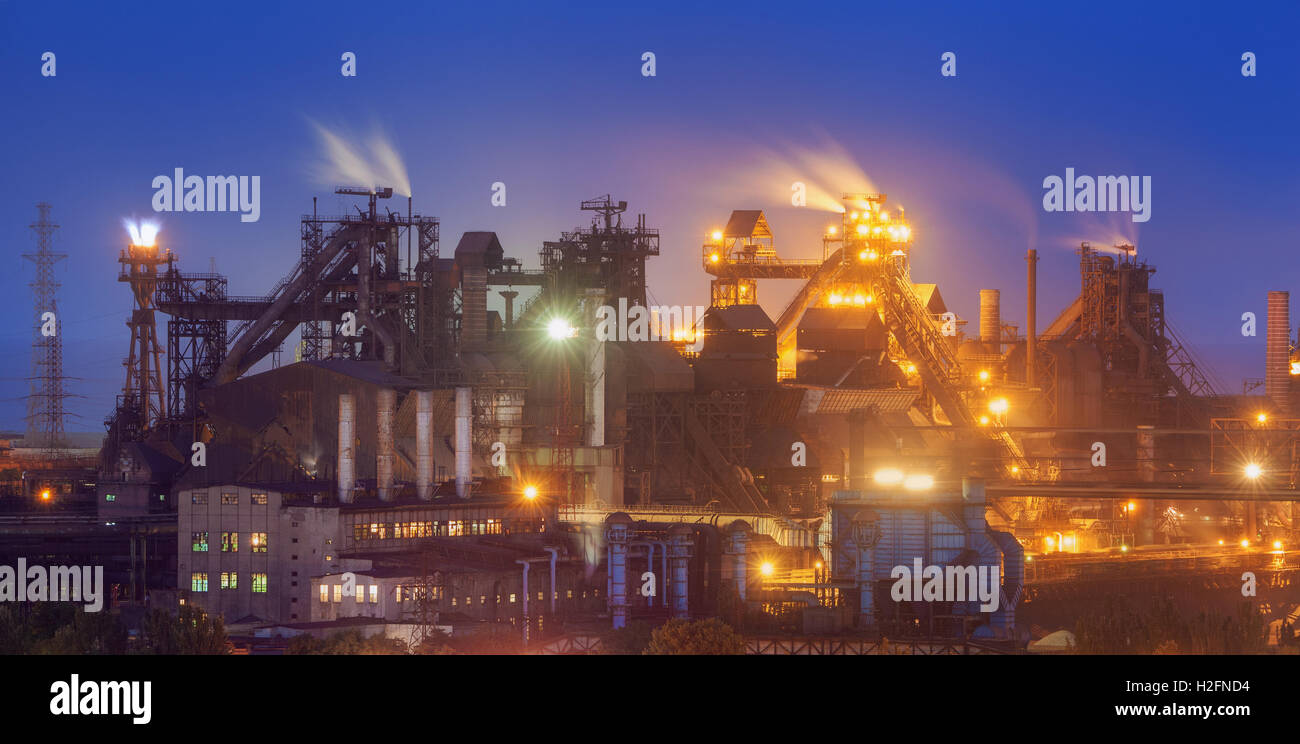 Stabilimento metallurgico di notte. Fabbrica di acciaio con fumaioli. Acciaierie e lavori di ferro. Industria pesante in Europa. Inquinamento atmosferico fr Foto Stock
