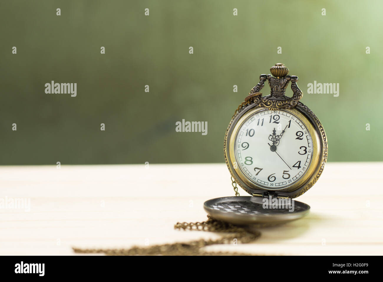 Antico orologio sul pavimento in legno e muro verde dello sfondo. Foto Stock