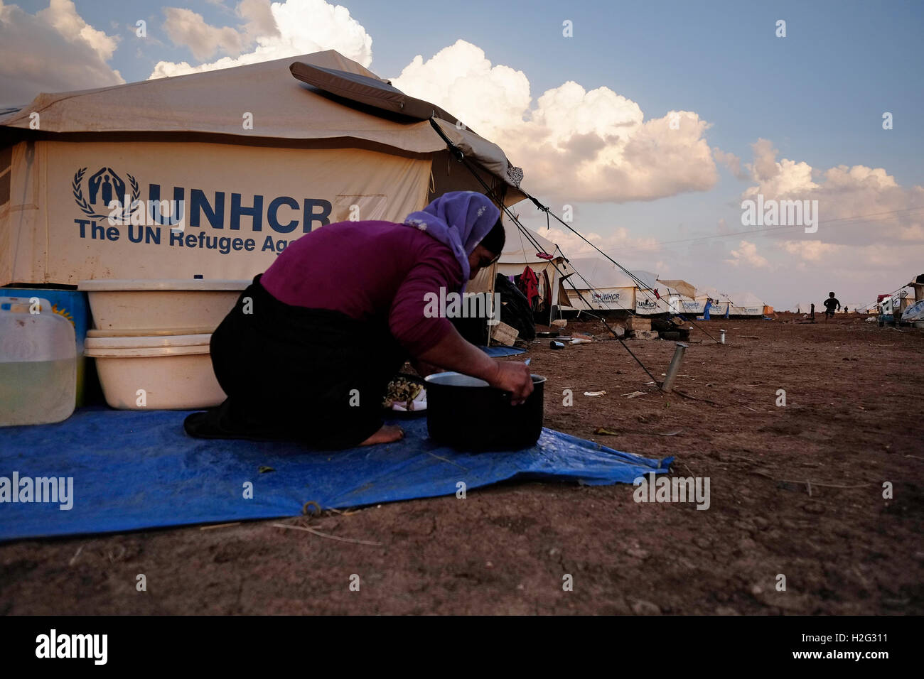 Una donna Yazidi preparare cibi accanto a una tenda UNHCR in Nawroz Refugee Camp che è stata inizialmente istituita per shelter Aramei spostato dall'attuale siria guerra civile poi occupata dagli sfollati dalla minoranza setta Yazidi, che fuggono dalla violenza nella città irachena di Sinjar situato vicino alla città di al-Malikyah in Rojava autonoma curda, regione nord-orientale della Siria. Foto Stock