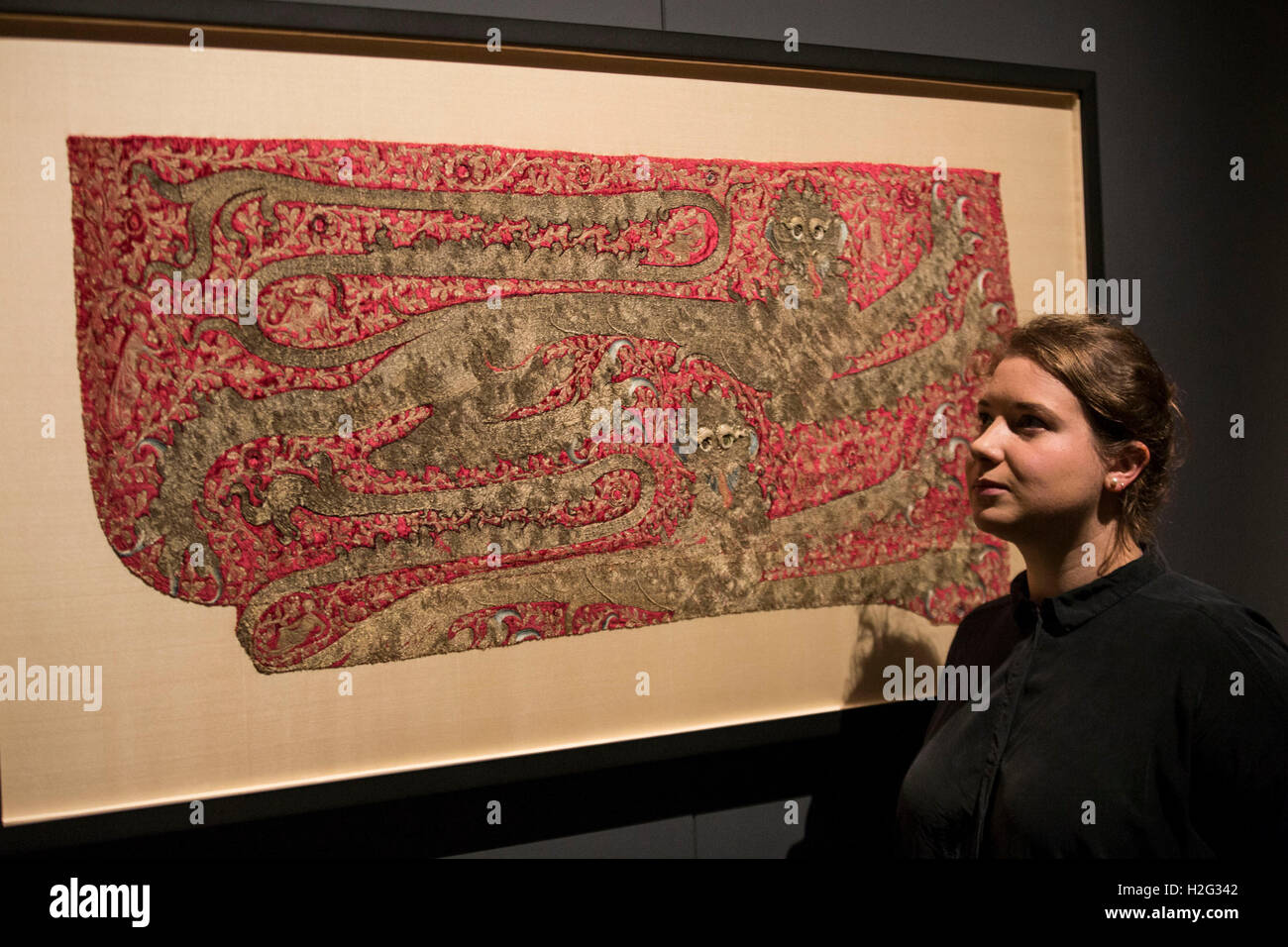 Una donna che guarda la parte del cavallo di un cacciatore di animali da pelliccia sul display come parte dell'Opus Anglicanum: Capolavori di Inglese Medievale mostra di ricamo presso il Victoria and Albert Museum (V&A) a Londra. Foto Stock