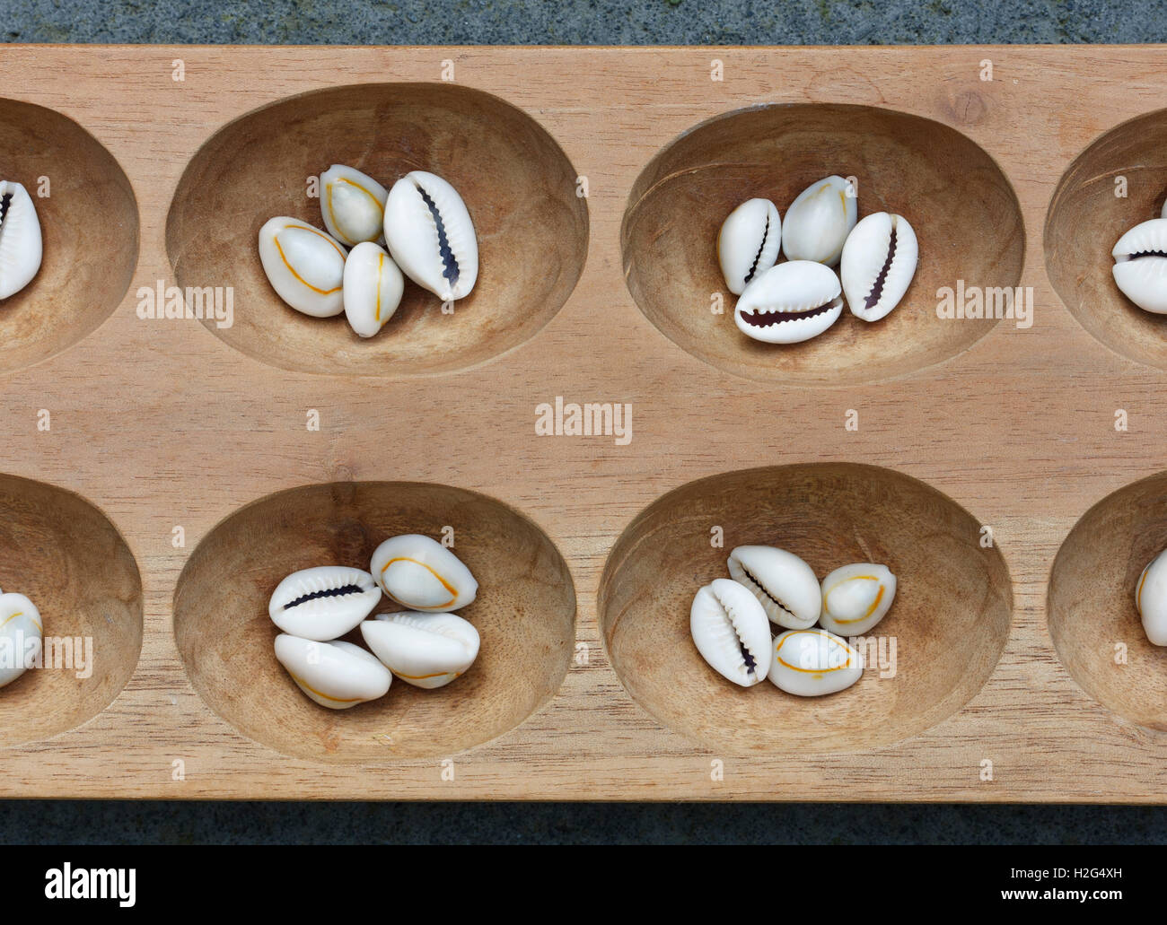 Dettaglio di un mancala board con conchiglie. Mancala è un tradizionale gioco da tavolo giocato in tutto il mondo. Foto Stock