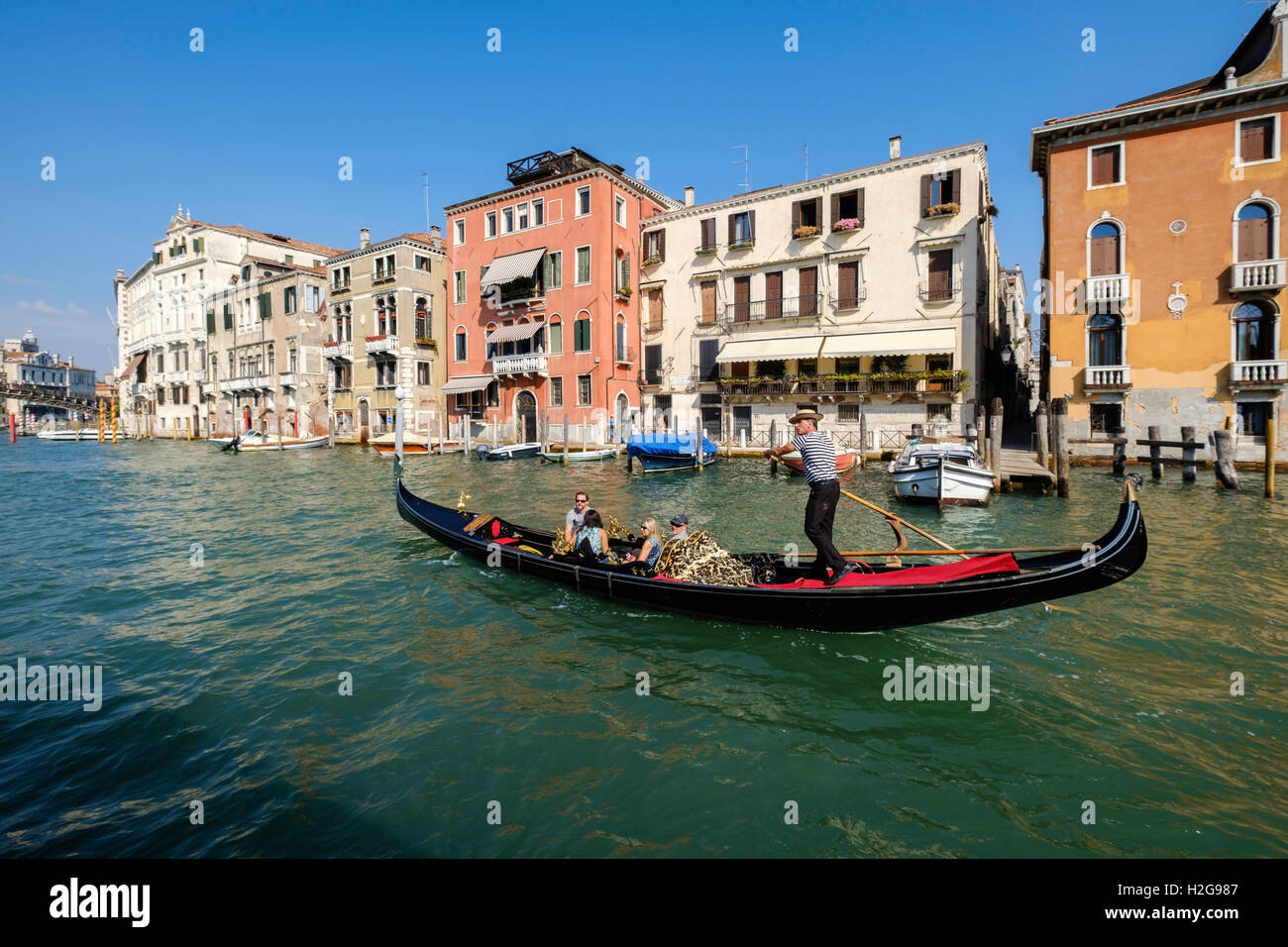 Gondola sul Canal Grande con passeggeri per turismo a Venezia, Italia Avvicinamento ponte sul Canal Grande. Tarda estate, cielo blu Foto Stock
