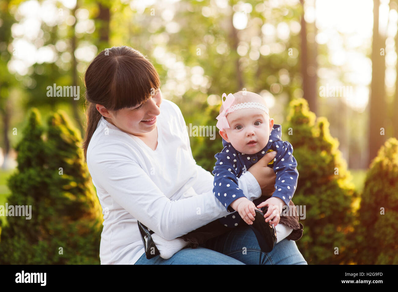 Giovane madre portante una bambina e passeggiate nel parco Foto Stock