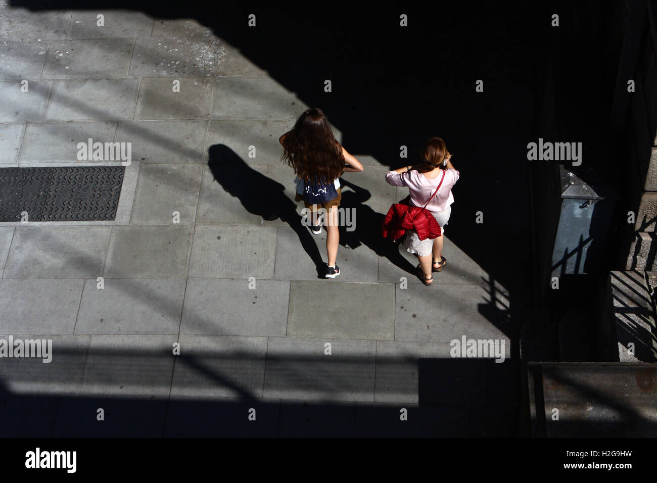 Due femmine passeggiate lungo gli argini del fiume Tamigi, Londra, Inghilterra sotto Hungerford ponte ferroviario. Foto Stock