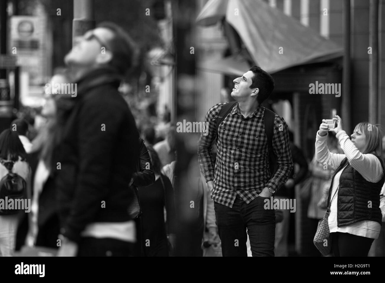 Tre persone in strada guardando verso l'alto - uno scatto di una foto. Foto Stock