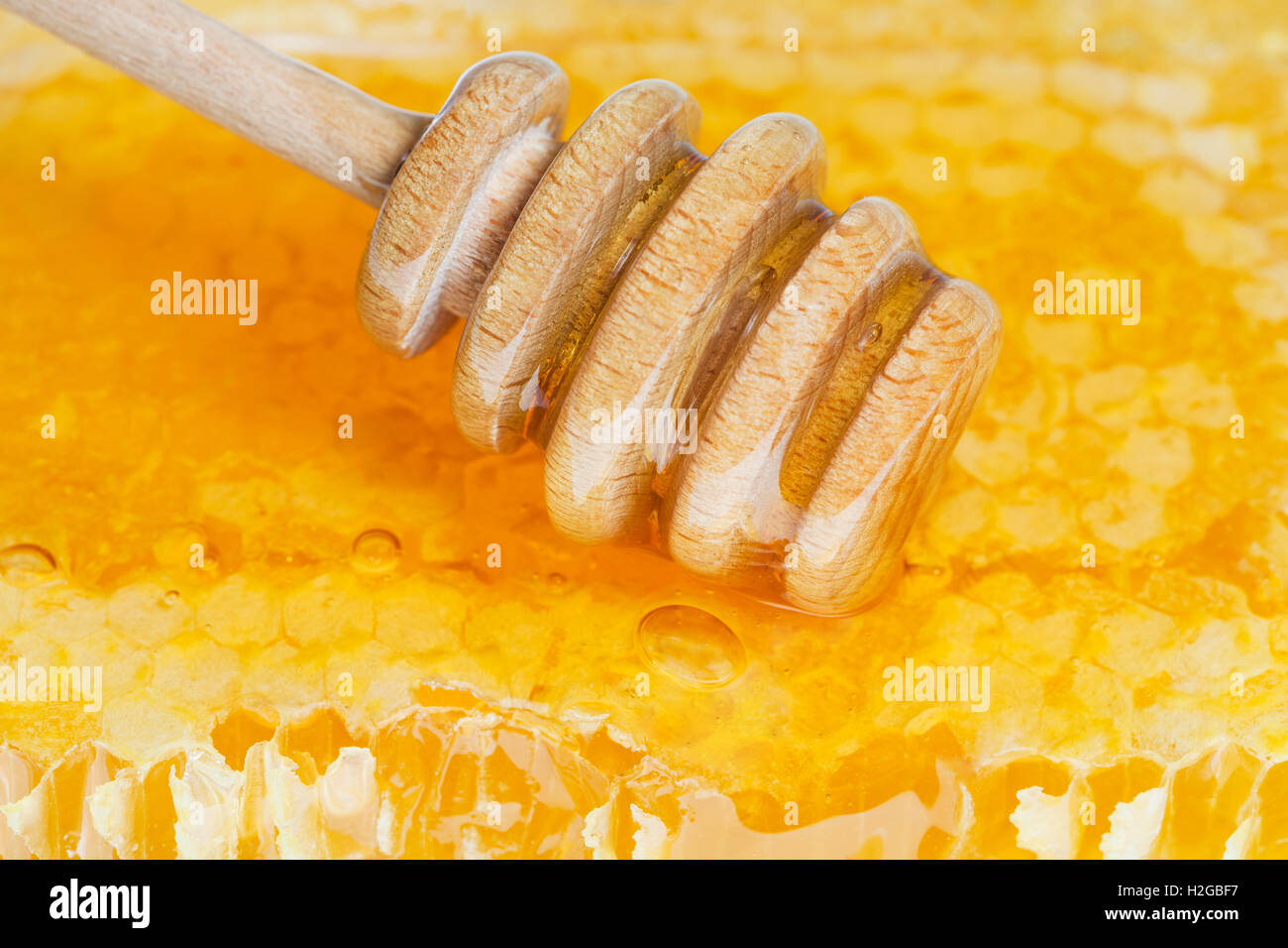 Legno cucchiaio di miele sulla superficie del favo di miele Foto Stock