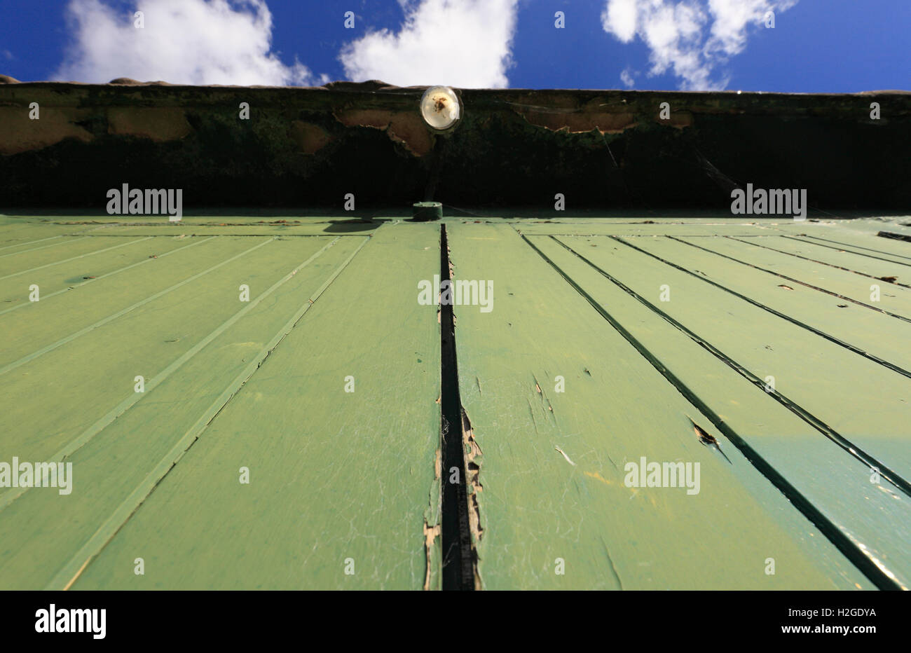 La ricerca di verde le porte dipinte di un overhead della lampadina della luce e una sezione di cielo. Foto Stock