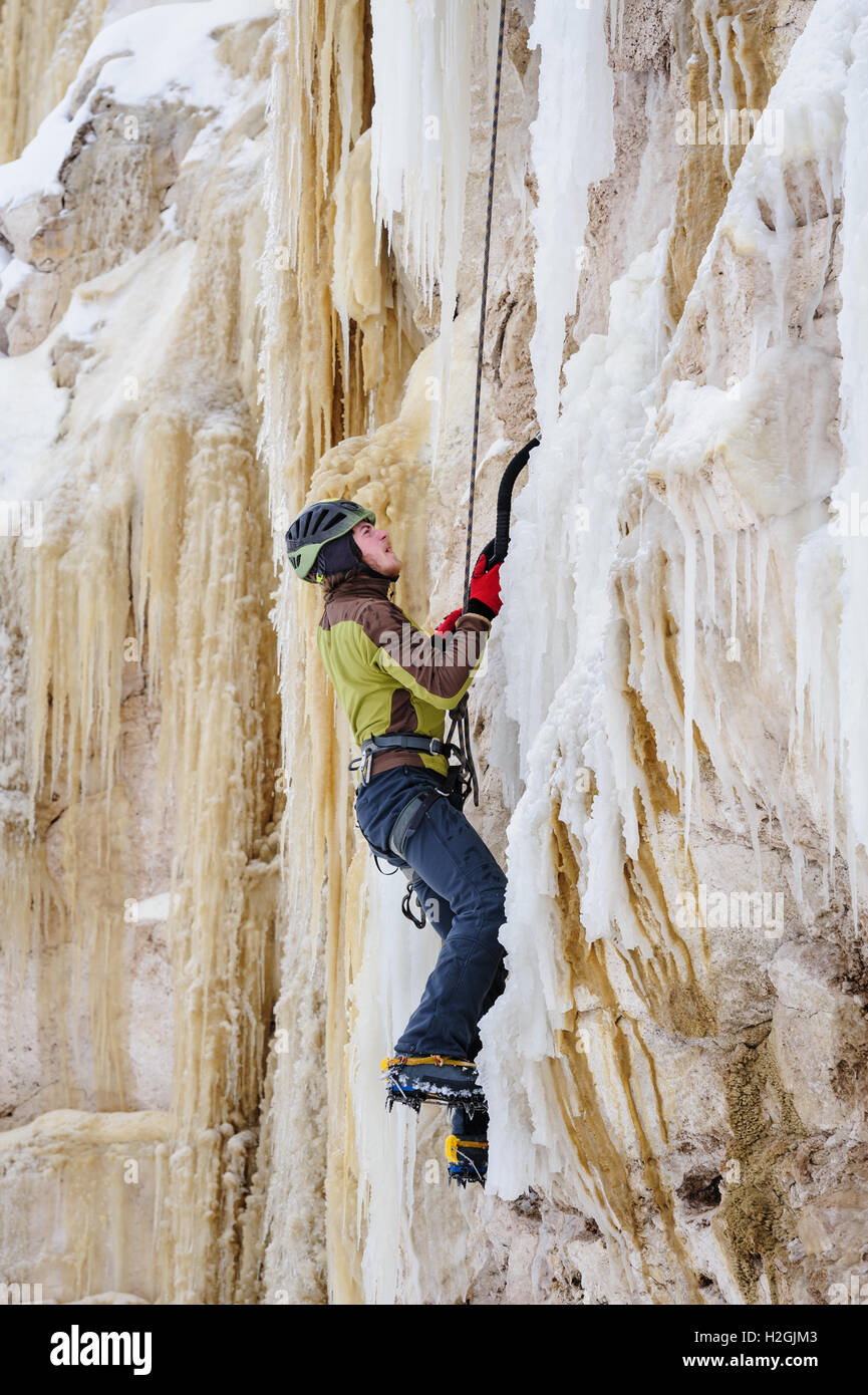 Giovane uomo arrampicata sul ghiaccio Foto Stock