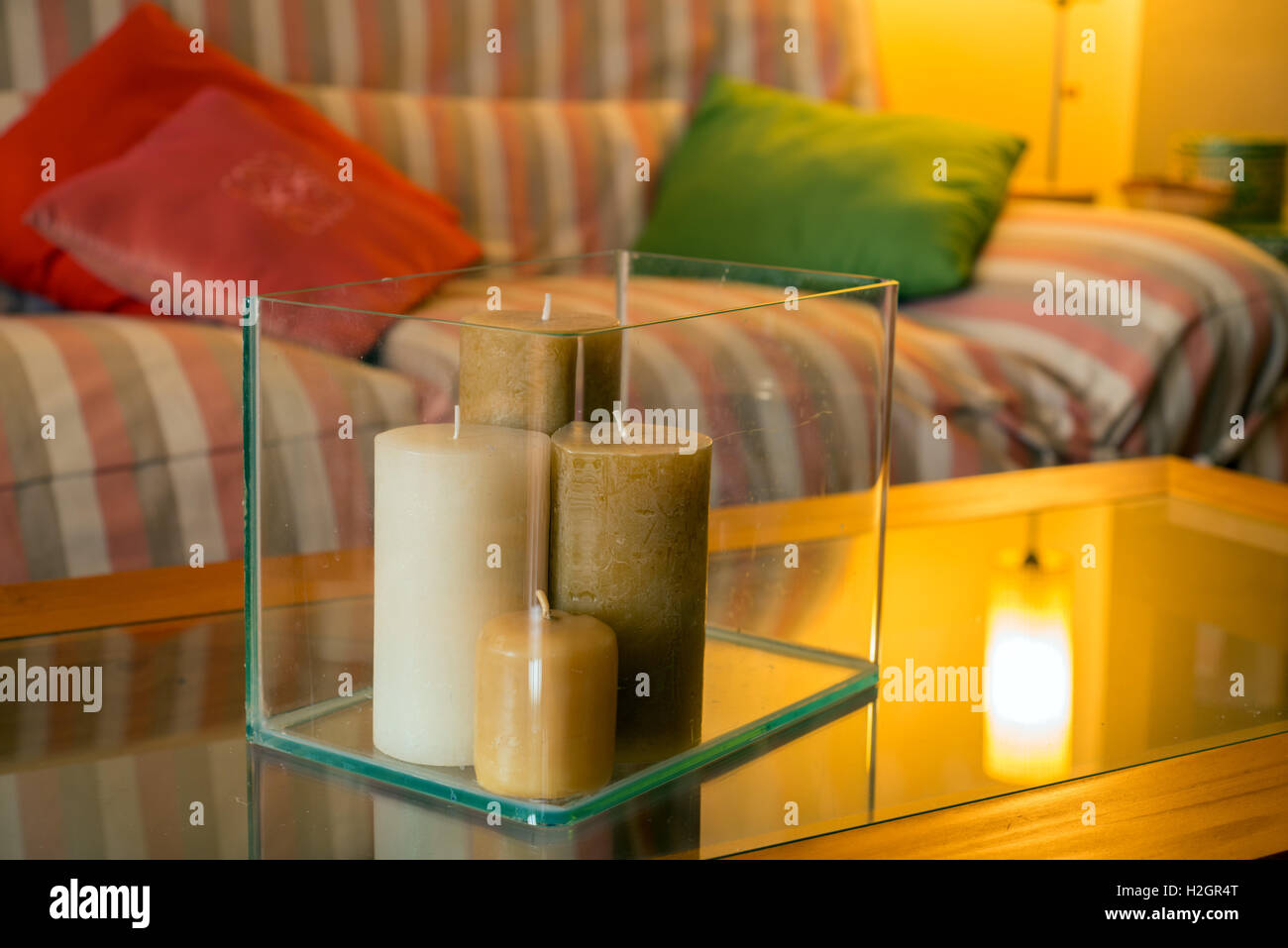 Tavolo da caffè in legno con candele e comodi divani con cuscini. Soggiorno interno e home decor concetto. Immagine dai toni Foto Stock