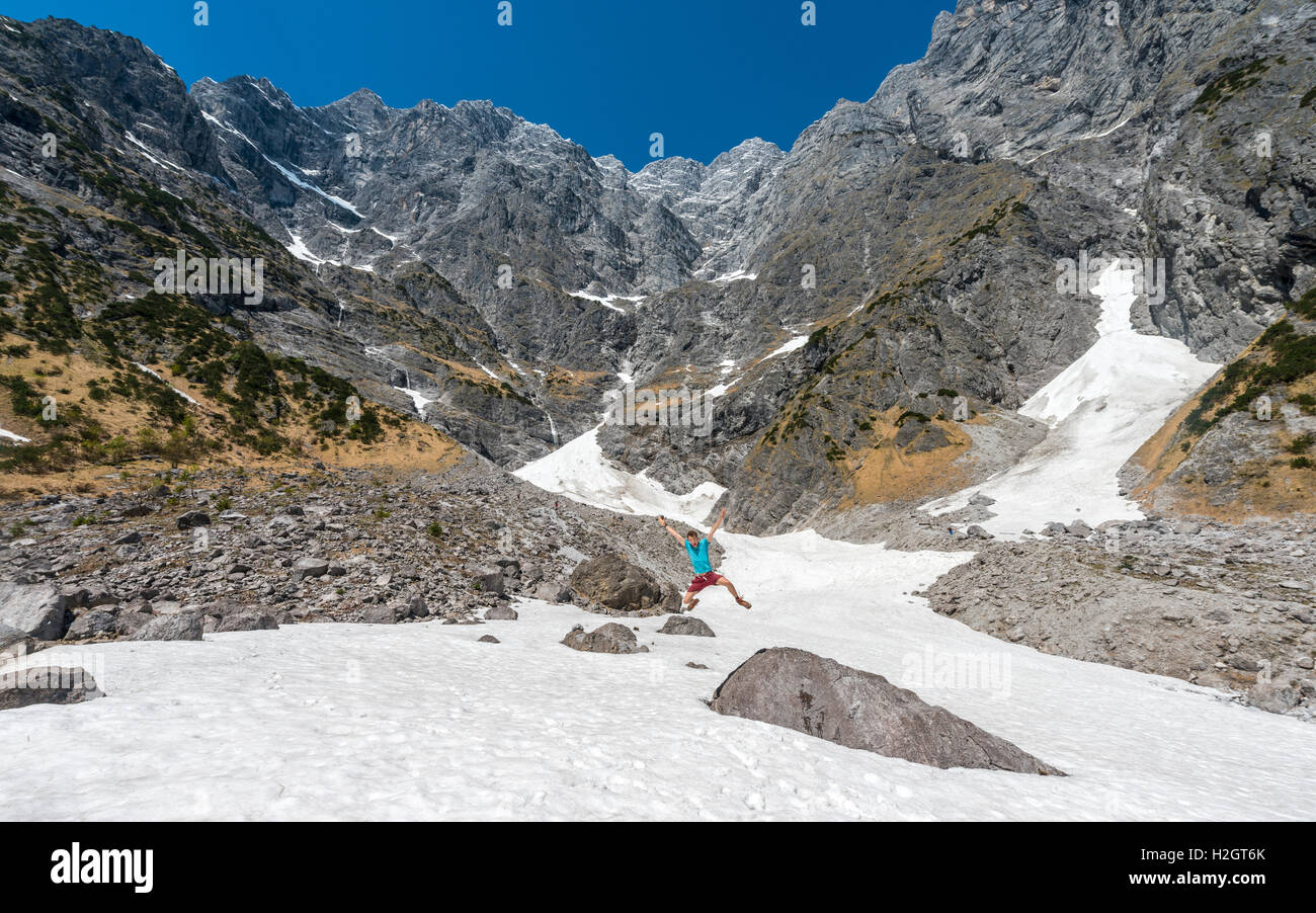 Giovane uomo jumping, campo di neve, Watzmann versante orientale, , Distretto di Berchtesgaden, Alta Baviera, Baviera, Germania Foto Stock