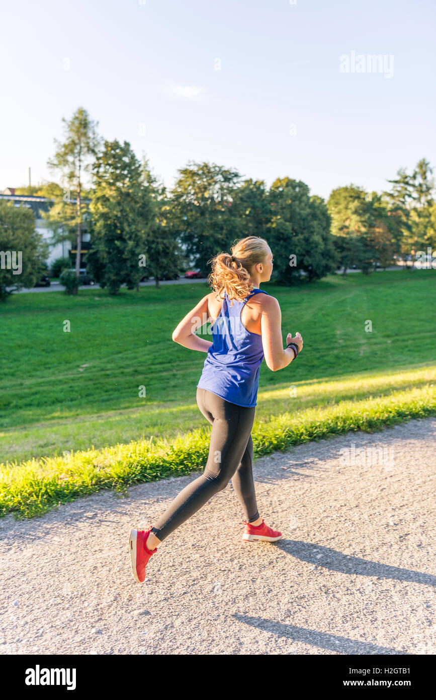 Giovane donna in abbigliamento sportivo a fare jogging nel parco, Monaco di Baviera, Baviera, Baviera, Germania Foto Stock