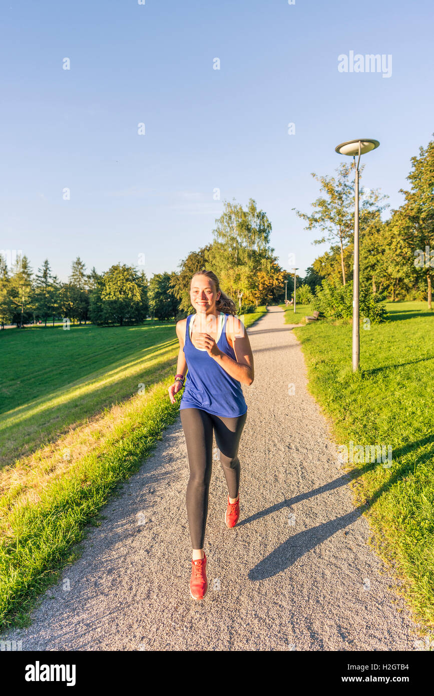 Giovane donna in abbigliamento sportivo a fare jogging nel parco, Monaco di Baviera, Baviera, Baviera, Germania Foto Stock