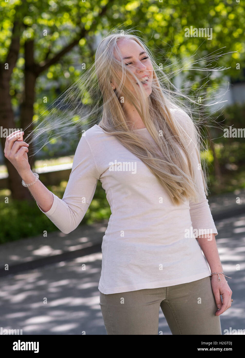 18 anno di età giovane donna con soffiaggio lunghi capelli biondi Foto Stock