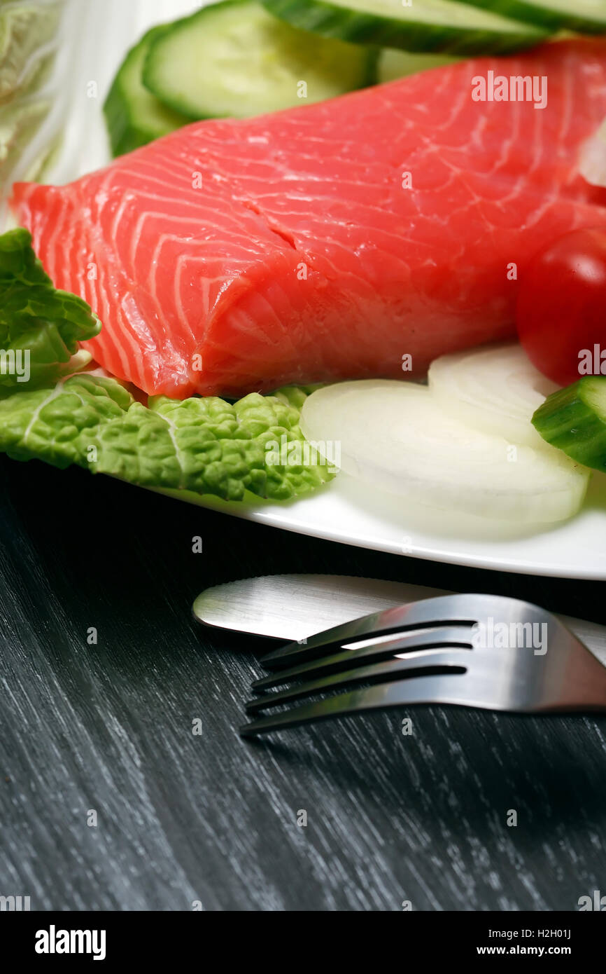 Primo piano di filetti di salmone e verdure sulla piastra vicino a forchetta e coltello Foto Stock