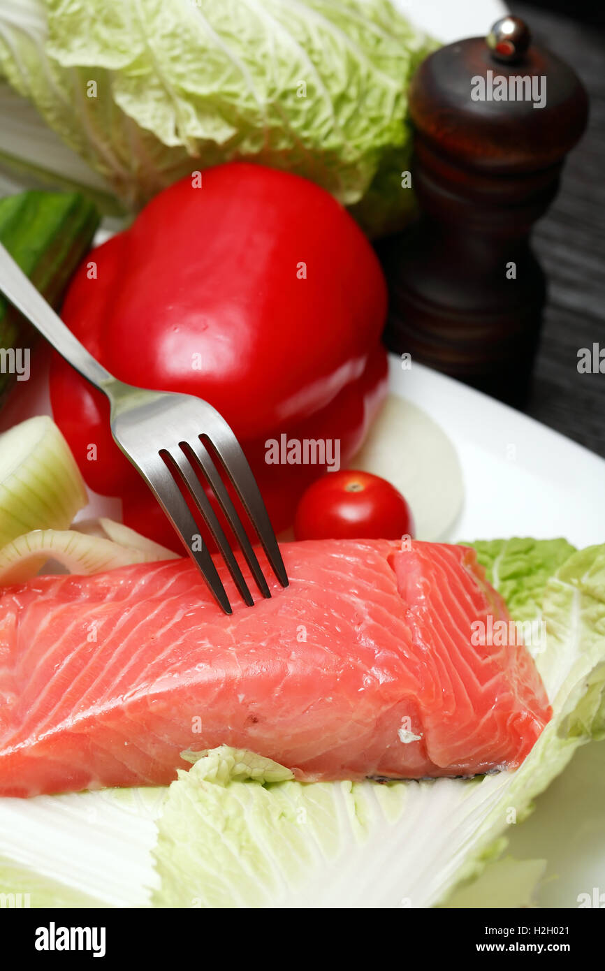 Primo piano di filetti di salmone e verdure sulla piastra vicino a forcella Foto Stock