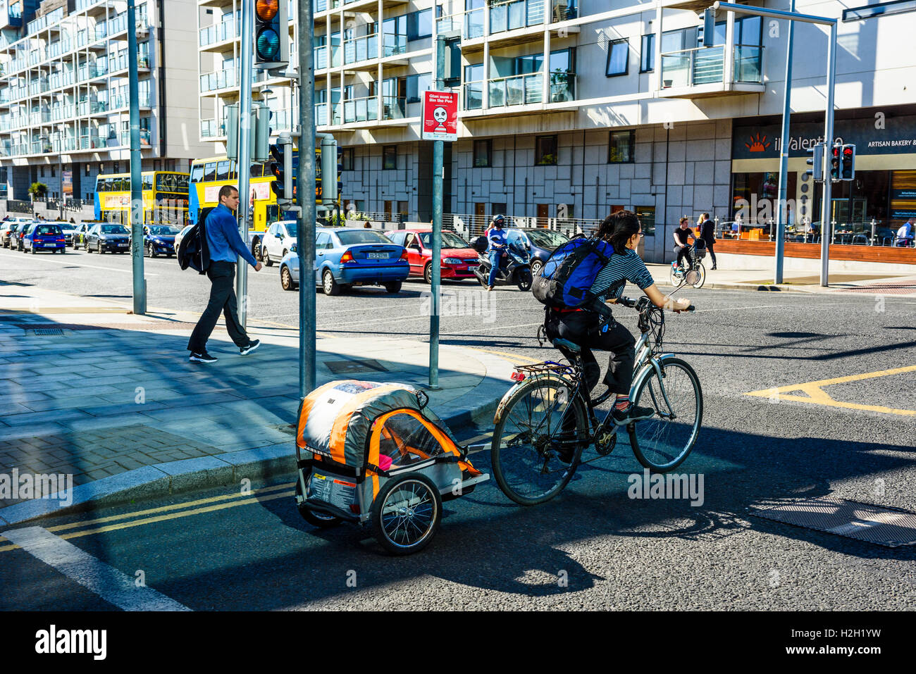 Ciclista con rimorchio bambino allo svincolo di Grand Canal Quay e Pearse Street Dublino Irlanda Foto Stock