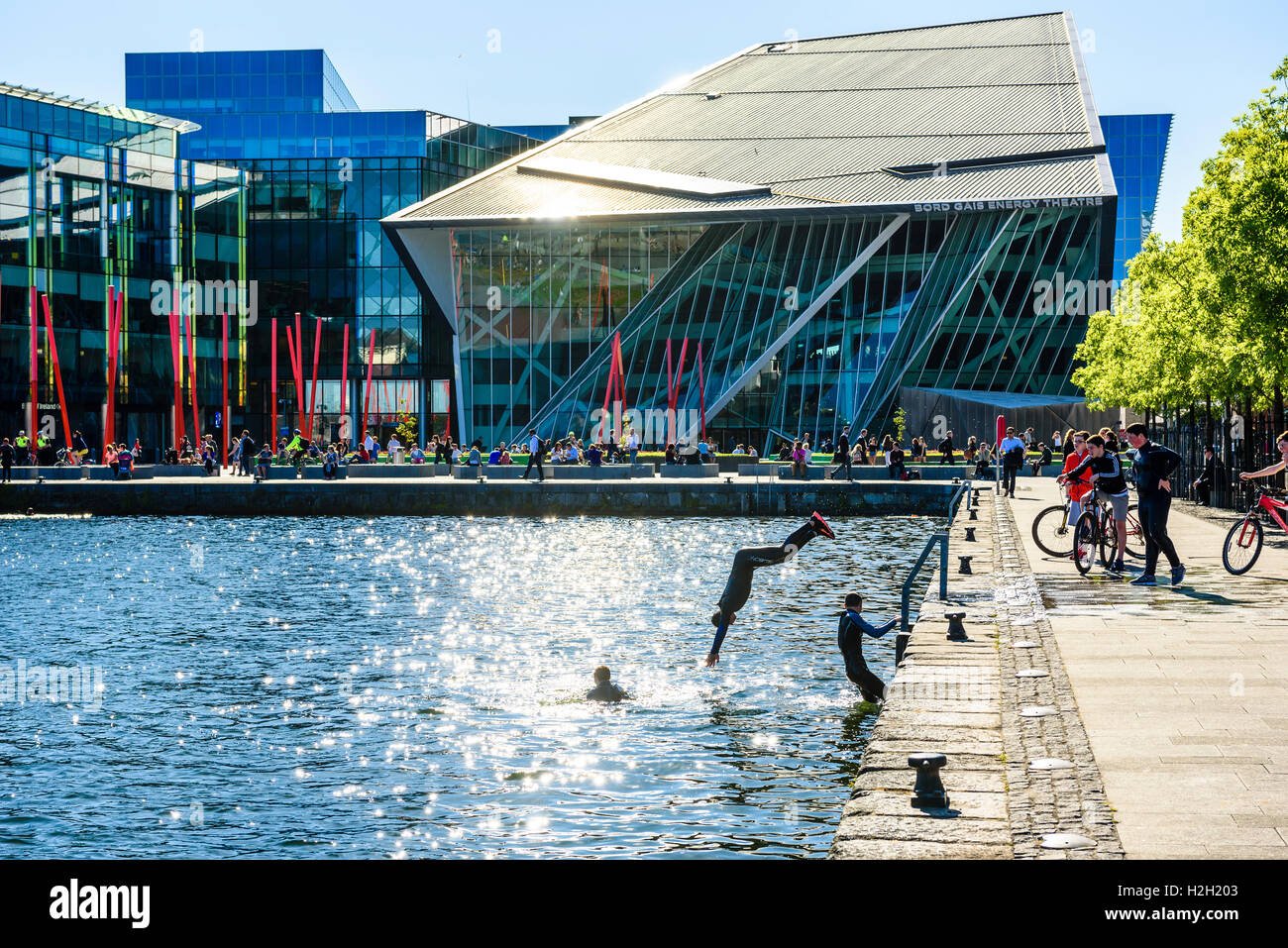 Ragazzi saltare in acqua a Hanover Quay a Dublino del Canal Grande con Bord Gáis energia dietro il Teatro Foto Stock