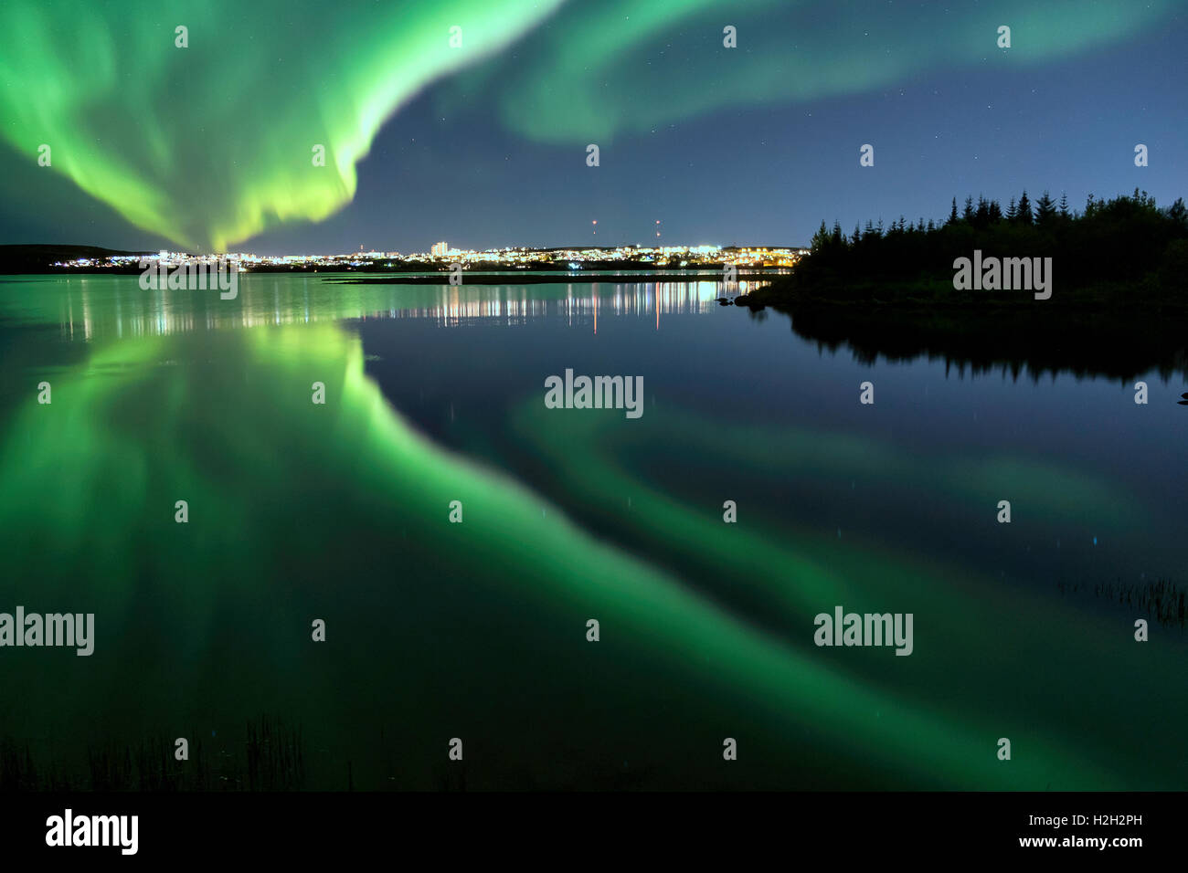 Auroras over Eillidavatn vicino a Reykjavik in Islanda. acqua calma che riflettono le luci del nord sfolgorante nel cielo. Foto Stock