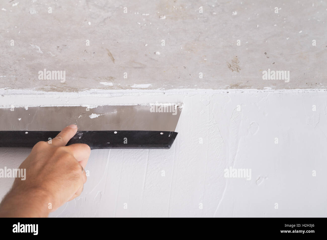 Miglioramento della casa da lavoratore mette lo strato di finitura di stucco sulla parete utilizzando una spatola di intonacatura Foto Stock