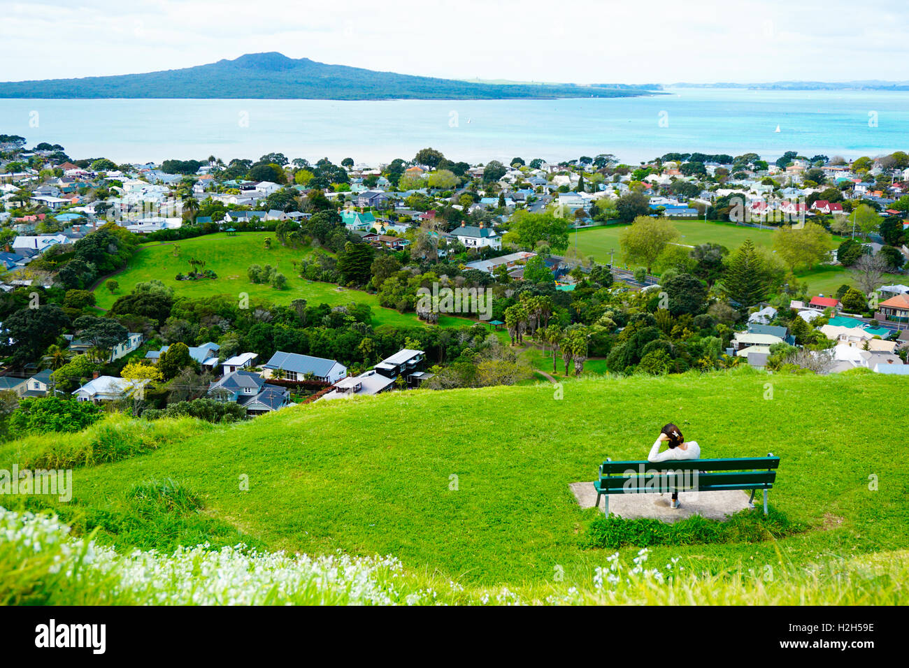 Lone donna seduta sul banco di lavoro e guardando all'oceano dalla sommità del monte Eden Foto Stock